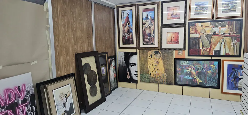 Framed artwork hung close together from floor to ceiling